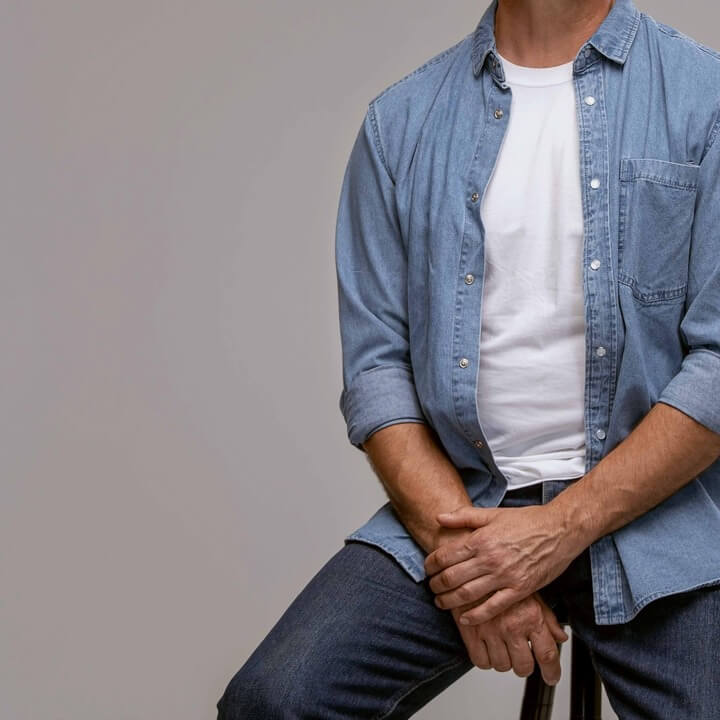 Hombre de media edad, sentado en una silla alta, enfocado de cuello a rodillas